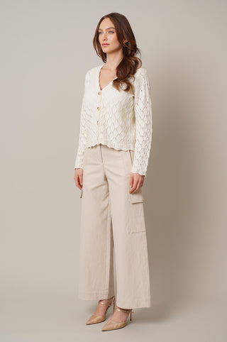 Model is wearing the cable knit button down cardigan by Cyrus in Cream