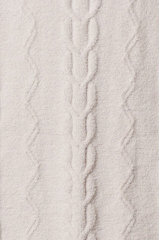 Close up of cream colored fabric with weaved patterns.