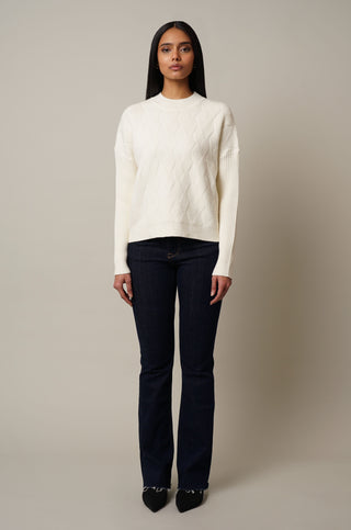 Model is wearing the Mock Neck Cable Knit Pullover in Cream.