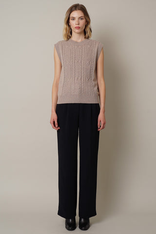 model is wearing the cable knit sleeveless top by cyrus in buckskin heather