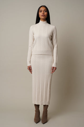 Model is wearing the Novelty Cable Knit Mock Neck Pullover in Cream.