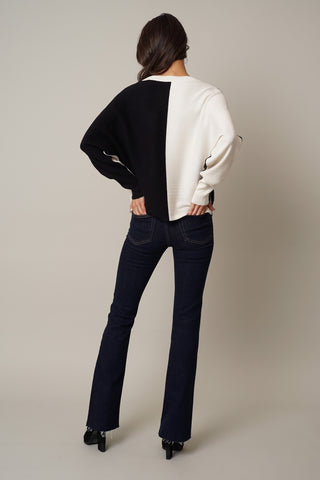 The back view of a woman wearing a black and white Cyrus Color Block Dolman sweater.