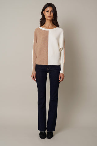 The model is wearing a white Cyrus Color Block Dolman sweater with flared jeans.