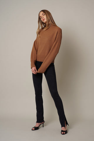 model is wearing the high mock neck sweater by cyrus in tobacco brown
