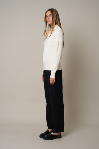 A model wearing a half zip sweater by Cyrus in cream.