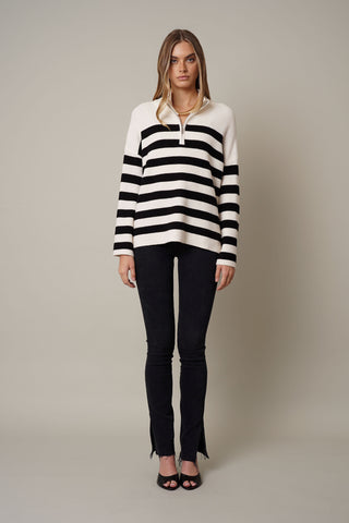 A model wearing a half zip striped sweater by Cyrus in cream and black.