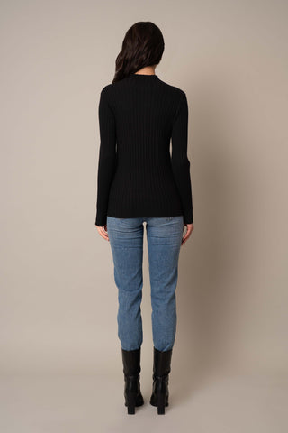 Model is wearing the Mock Neck Ribbed Pullover in Black.