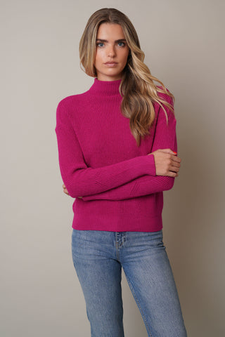 Model is wearing the Ribbed Funnel Neck Sweater with Slit Cuffby Cyrus in Cerise